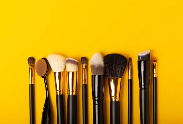 Set of cosmetic brushes on a yellow background. Makeup brushes. Makeup tool. Beauty concept.Professional brushes for applying cosmetics eyeshadows, make-up powder. Place for text. Copy space. Flat lay.