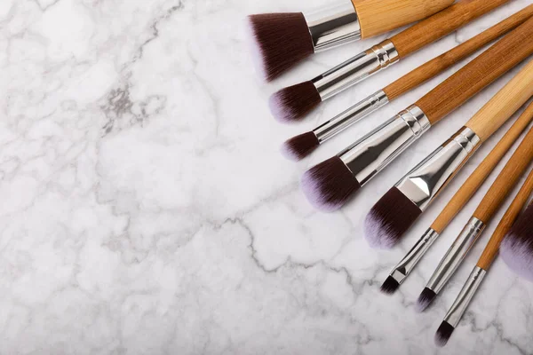 Set of cosmetic brushes on a white marble background. Makeup brushes. Makeup tool. Beauty concept.Professional brushes for applying cosmetics eyeshadows, make-up powder. Place for text. Copy space. Flat lay.