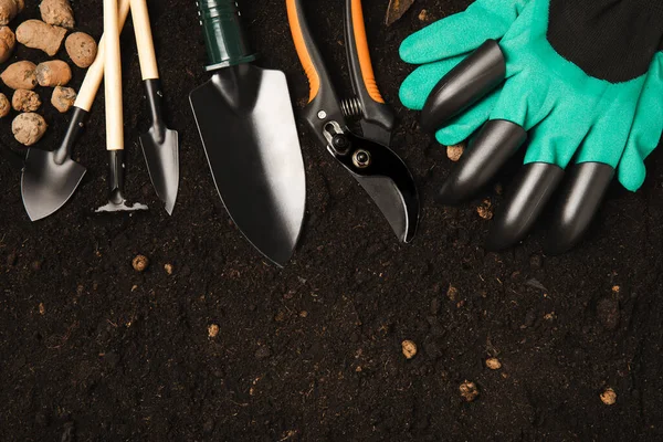 Garden tools and fertile soil. Garden rake, shovel, gloves, pruner and fertilizer. Gardening concept. Top view. Place to copy. Mocap. Banner.