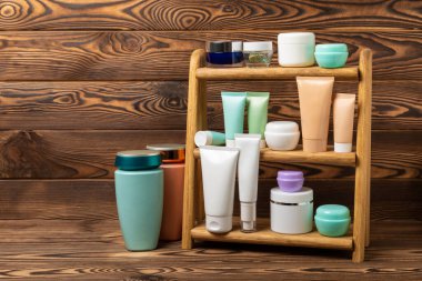 Kahverengi ahşap bir masada cilt bakım kozmetiği. Kozmetik tüpleri banyoda. Şampuan ve saç kremi. Raftaki yüz ve vücut için bakım ürünleri. Krem ve yüz yıkama, toner ve serum. MOCAP.