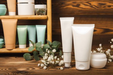 Kahverengi ahşap bir masada cilt bakım kozmetiği. Kozmetik tüpleri banyoda. Krem, serum ve yüz fırçası. Yüz bakımı konsepti. MOCAP.