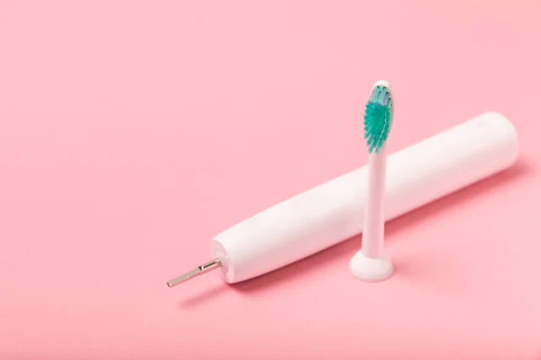 Electronic ultrasonic toothbrush on a pink background.Smart electric toothbrush. Items for dental care and caries prevention. Dentistry concept. Modern technologies for health. Healthy teeth.