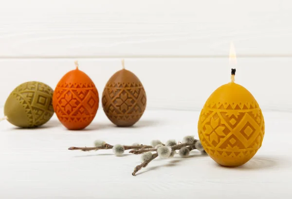 Easter candle eggs and willow branches on a white textural background. Easter holiday concept.Spring willow bouquet.Decor for home and festive steel.Copy space. Place for text.