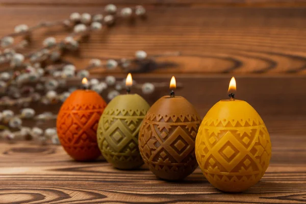 Easter candle eggs and willow branches on a brown textural background. Easter holiday concept.Spring willow bouquet.Decor for home and festive steel.Copy space. Place for text.