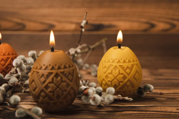 Easter candle eggs and willow branches on a brown textural background. Easter holiday concept.Spring willow bouquet.Decor for home and festive steel.Copy space. Place for text.