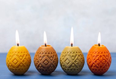 Mavi arka planda Paskalya yumurtaları mumları. Yan manzara. Tasarım. Tatil konsepti. Mutlu Paskalyalar. Paskalya tatili konsepti. Ev ve festival çeliği için dekor. Metin için yer.