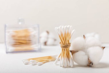 Hafif beton zeminde pamuk tomurcukları. Çevre dostu malzemeler. Tahta, beyaz bir zeminde pamuk örnekleri. Bambu bezleri ve pamuk çiçekleri. Sıfır atık, plastiksiz yaşam tarzı..