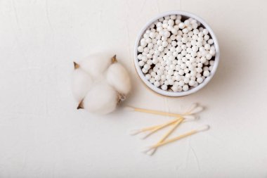 Hafif beton zeminde pamuk tomurcukları. Çevre dostu malzemeler. Tahta, beyaz bir zeminde pamuk örnekleri. Bambu bezleri ve pamuk çiçekleri. Sıfır atık, plastiksiz yaşam tarzı..