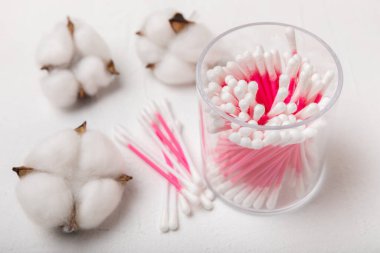 Hafif beton zeminde pamuk tomurcukları. Dokusal arka planda pamuk çiçekli hijyenik pamuk çubukları. Kulak çubukları. Mesaj için yer. Kopyalanacak yer. Yakın plan..