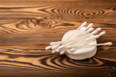 Kahverengi arka planda pamuk tomurcukları. Dokuların arka planında hijyenik pamuk çubukları ve pamuk pedleri var. Kulak çubukları. Mesaj için yer. Kopyalanacak yer. Yakın plan..