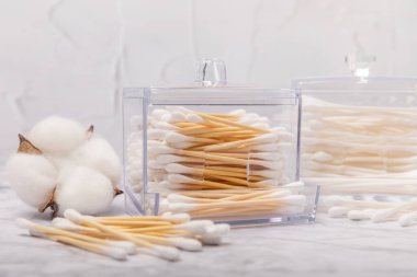 Hafif beton zeminde pamuk tomurcukları. Çevre dostu malzemeler. Tahta, beyaz bir zeminde pamuk örnekleri. Bambu bezleri ve pamuk çiçekleri. Sıfır atık, plastiksiz yaşam tarzı..