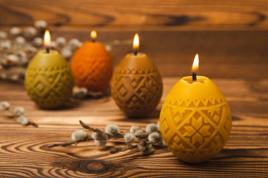 Geleneksel Paskalya dekoru. Renkli yumurta şeklinde soya mumları ve kahverengi desenli arka planda söğüt dalları yakmak. Mutlu Paskalyalar. Arka planda renkli paskalya mumları ve çiçekler. Boşluğu kopyala..