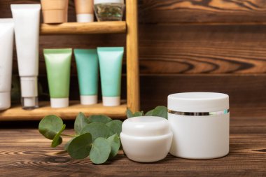 Kahverengi ahşap arka planda, banyoda kozmetik ürünleri olan bir raf. Yıkama jeli, toner, serum ve vücut kremi. Kozmetik tüpü. Dekoratif ve bakım kozmetik. Güzellik konsepti. Metin için yer. Boşluğu kopyala.