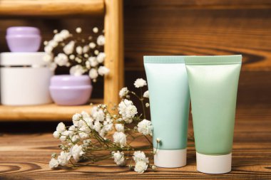 Kahverengi ahşap arka planda, banyoda kozmetik ürünleri olan bir raf. Yıkama jeli, toner, serum ve vücut kremi. Kozmetik tüpü. Dekoratif ve bakım kozmetik. Güzellik konsepti. Metin için yer. Boşluğu kopyala.