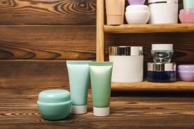 Kahverengi ahşap arka planda, banyoda kozmetik ürünleri olan bir raf. Yıkama jeli, toner, serum ve vücut kremi. Kozmetik tüpü. Dekoratif ve bakım kozmetik. Güzellik konsepti. Metin için yer. Boşluğu kopyala.