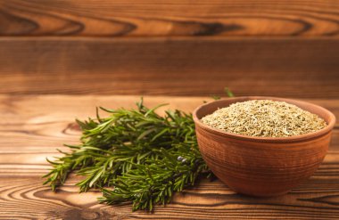 Kırsal bir kasede kurutulmuş biberiye, kahverengi ahşap arka planda taze biberiye dalları et ve balık için bitki. Yemek tarifi. Organik bitkiler. Metin için yer.