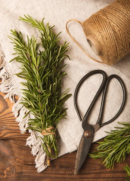 Fresh rosemary herb and vintage scissors on brown wood.Bunch of fresh fragrant rosemary. Spices and herbs for meat and fish. Recipe. Culinary concept.Organic herbs.Place for text. Space for copy. Flat lay.