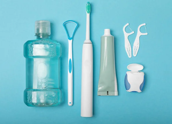 Toothbrush,electric toothbrush,tongue cleaner, floss, toothpaste tube and mouthwash on blue background with copy space. Flat lay. Dental hygiene. Oral care kit. Dentist concept.Dental care.
