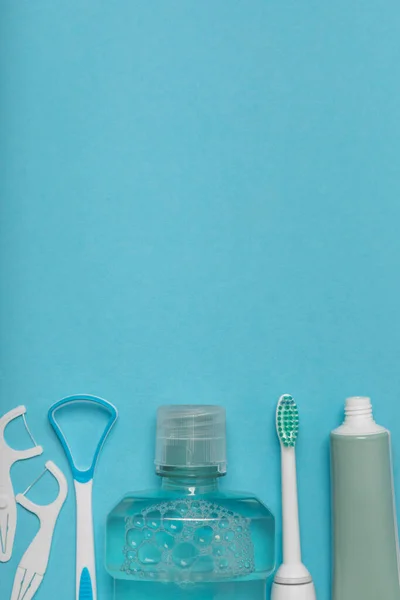 Toothbrush,electric toothbrush,tongue cleaner, floss, toothpaste tube and mouthwash on blue background with copy space. Flat lay. Dental hygiene. Oral care kit. Dentist concept.Dental care.