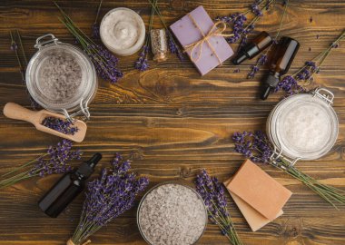 Lavanta kaplıcası. Temel yağlar, deniz tuzu, el yapımı sabun, krem ve vücut fırçası kahverengi desenli ahşap lavanta çiçekleri. Çiçekli doğal bitkisel kozmetik ürünleri ve lavanta aroması..