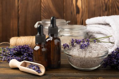 Lavanta kaplıcası. Temel yağlar, deniz tuzu, el yapımı sabun, krem ve vücut fırçası kahverengi desenli ahşap lavanta çiçekleri. Çiçekli doğal bitkisel kozmetik ürünleri ve lavanta aroması..