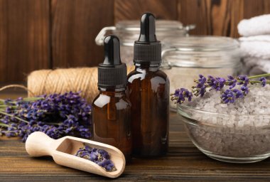 Lavanta kaplıcası. Temel yağlar, deniz tuzu, el yapımı sabun, krem ve vücut fırçası kahverengi desenli ahşap lavanta çiçekleri. Çiçekli doğal bitkisel kozmetik ürünleri ve lavanta aroması..
