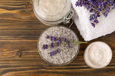 Lavanta kaplıcası. Temel yağlar, deniz tuzu, el yapımı sabun, krem ve vücut fırçası kahverengi desenli ahşap lavanta çiçekleri. Çiçekli doğal bitkisel kozmetik ürünleri ve lavanta aroması..