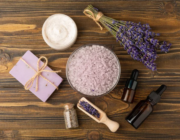 stock image Lavender spa. Essential oils, sea salt, handmade soap, cream and body scrub with lavender flowers on brown texture wood. Natural herbal cosmetics with flowers and lavender aroma.Aromatherapy and relax.