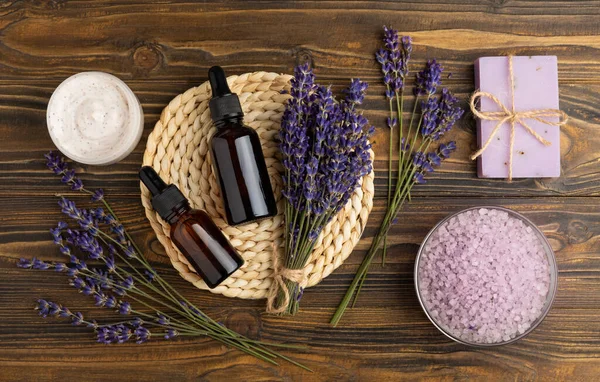 stock image Lavender spa. Essential oils, sea salt, handmade soap, cream and body scrub with lavender flowers on brown texture wood. Natural herbal cosmetics with flowers and lavender aroma.Aromatherapy and relax.