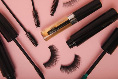 Takma kirpikler, rimel ve kirpik fırçaları, pembe arka planda kirpik bigudileri. Makyaj aletleri. Güzellik konsepti. Makyaj. Mesaj için yer. Kopyalama yeri. Düz çizgi. MOCAP.