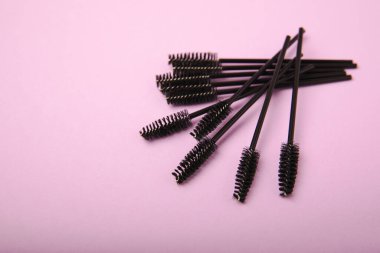 Leylak arka planında kirpik uzatma fırçaları. Uzun ve takma kirpikleri taramak için fırça. Kirpikleri ve kaşları düzeltmek için fırçala.