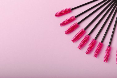 Leylak arka planında kirpik uzatma fırçaları. Uzun ve takma kirpikleri taramak için fırça. Kirpikleri ve kaşları düzeltmek için fırçala.