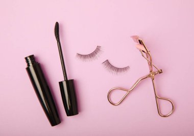 Takma kirpikli, rimel ve kirpik fırçalı, leylak arkaplanda kirpik bigudileri. Makyaj aletleri. Güzellik konsepti. Beste yap. Mesaj için yer. Kopyalanacak yer. Düz çizgi. MOCAP.