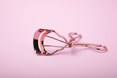 Kirpik bigudisi için eflatun arka planda kirpik bigudisi. Kirpik makyaj için temel ürünler. Kirpik kıvırma aleti. Makyaj. Güzellik konsepti. Yakın plan..