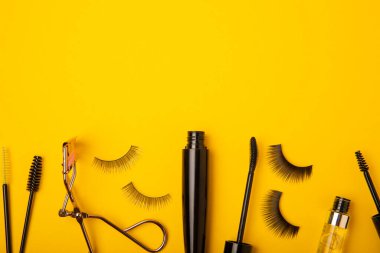 Takma kirpikler, rimel ve kirpik fırçaları, sarı arka planda kirpik bigudileri. Makyaj aletleri. Güzellik konsepti. Beste yap. Mesaj için yer. Kopyalanacak yer. Düz çizgi. MOCAP.