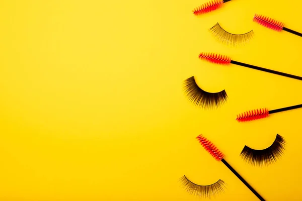 Brushes for eyelash extension on a yellow background. Brush for combing extended and false eyelashes. Brush for straightening eyelashes and eyebrows.