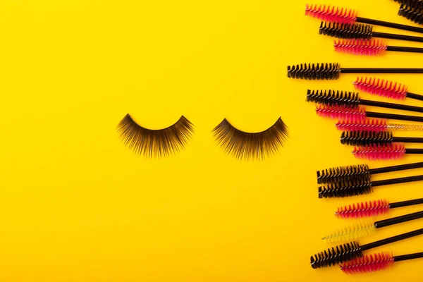 Brushes for eyelash extension on a yellow background. Brush for combing extended and false eyelashes. Brush for straightening eyelashes and eyebrows.