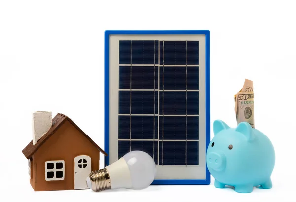 Solar panel, led lamp, house model, money and piggy bank isolated on white background. The concept of saving money and clean energy. Concept of ecology and sustainable development.