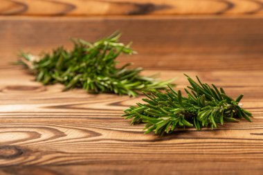 Kahverengi desenli ahşap arka planda biberiye. Taze baharat. Et ve balık çeşnisi. Yemek tarifi. Masada bir buket taze biberiye var. Mesaj için yer. Kopyalanacak yer.