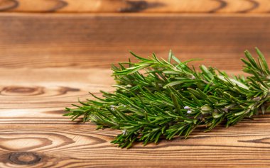 Kahverengi desenli ahşap arka planda biberiye. Taze baharat. Et ve balık çeşnisi. Yemek tarifi. Masada bir buket taze biberiye var. Mesaj için yer. Kopyalanacak yer.