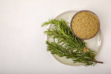 Taze biberiye ve kuru baharat tabakta ve beyaz dokuda kaşıklar. Taze baharat. Et ve balık çeşnisi. Yemek tarifi. Masada bir buket taze biberiye var. Metin için yer.