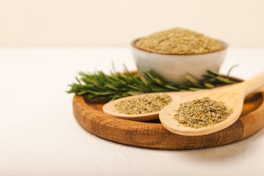 Taze biberiye ve kuru baharat tabakta ve beyaz dokuda kaşıklar. Taze baharat. Et ve balık çeşnisi. Yemek tarifi. Masada bir buket taze biberiye var. Metin için yer.