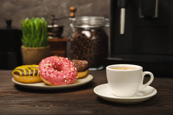 Fragrant delicious espresso coffee with pink strawberry donut, coffee machine on brown texture table. Good morning concept. Morning coffee. Sweet table. Colorful berry buns.Top view.