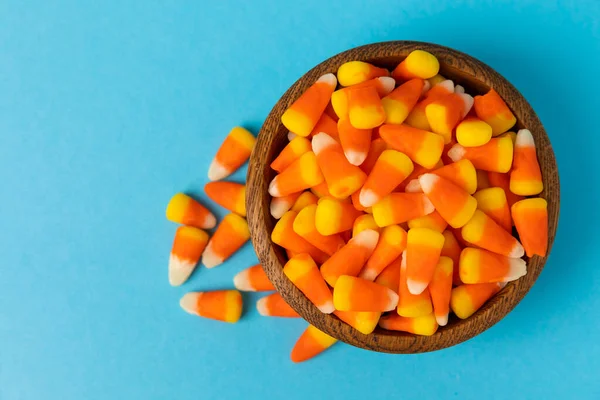 Halloween candy on a blue background. Corn candy. Holiday concept.Classic white, orange and yellow Halloween lollipops. Concept with candy corn and jack-o-lantern on colored background.