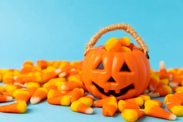 Halloween candy on a blue background. Corn candy. Holiday concept.Classic white, orange and yellow Halloween lollipops. Concept with candy corn and jack-o-lantern on colored background.