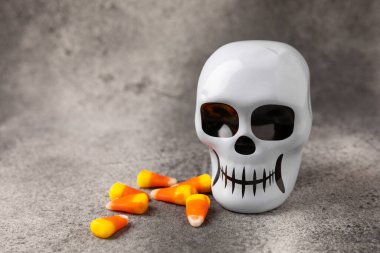 Cadılar Bayramı 'nda mısır şekeri ve şeker kafatası. Cadılar Bayramı için klasik şeker şekeri. Cadılar bayramı konsepti, mısır şekeri ve balkabağı..