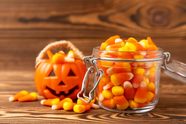Halloween candy corn on brown texture background.Classic white, orange and yellow candy corn sweets for Halloween with.copy space.Halloween holiday concept with candy corn and jack o lantern.