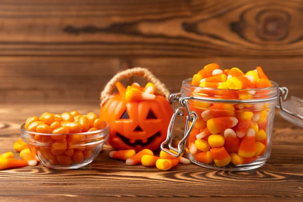 Halloween candy corn on brown texture background.Classic white, orange and yellow candy corn sweets for Halloween with.copy space.Halloween holiday concept with candy corn and jack o lantern.