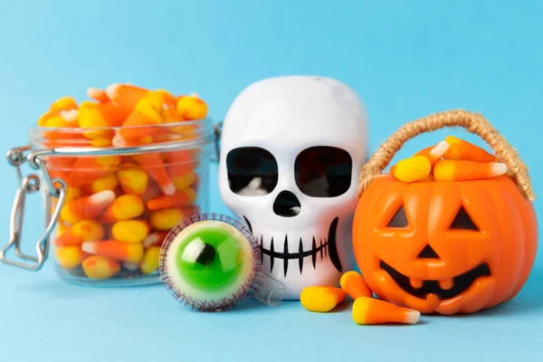 Halloween candy corn on blue texture background.Classic white, orange and yellow candy corn sweets for Halloween with.copy space.Halloween holiday concept with candy corn and jack o lantern.copy space
