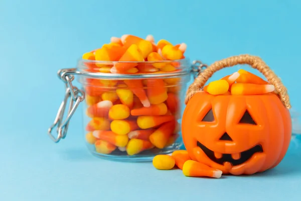 Halloween candy corn on blue texture background.Classic white, orange and yellow candy corn sweets for Halloween with.copy space.Halloween holiday concept with candy corn and jack o lantern.copy space